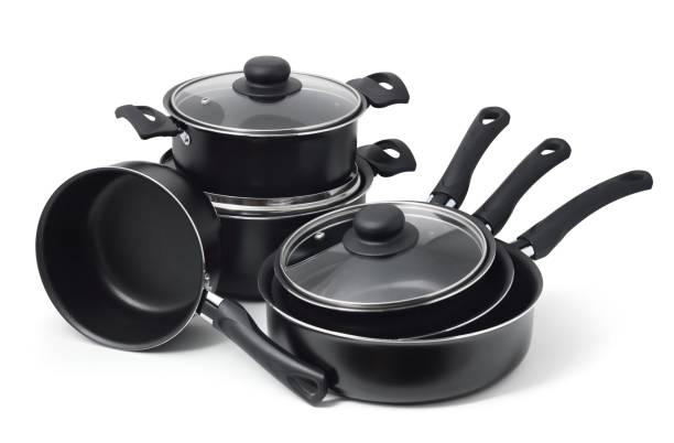 Set of black non-stick kitchen utensils on a white background. Pot, ladle, frying pan  with glass lid.